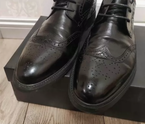 出黑色系带皮鞋,款式为商务休闲的布洛克雕花...