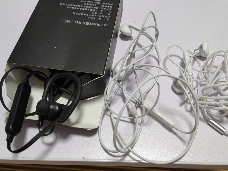 两个白色都是入耳机，黑色是蓝牙耳机，挂耳式